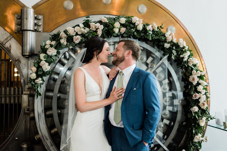 Bride and groom looking at each other in front of bank vault door